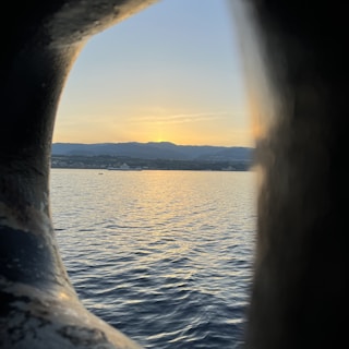 A serene sunset behind a glass-like rounded frame with a subtle elevation effect.