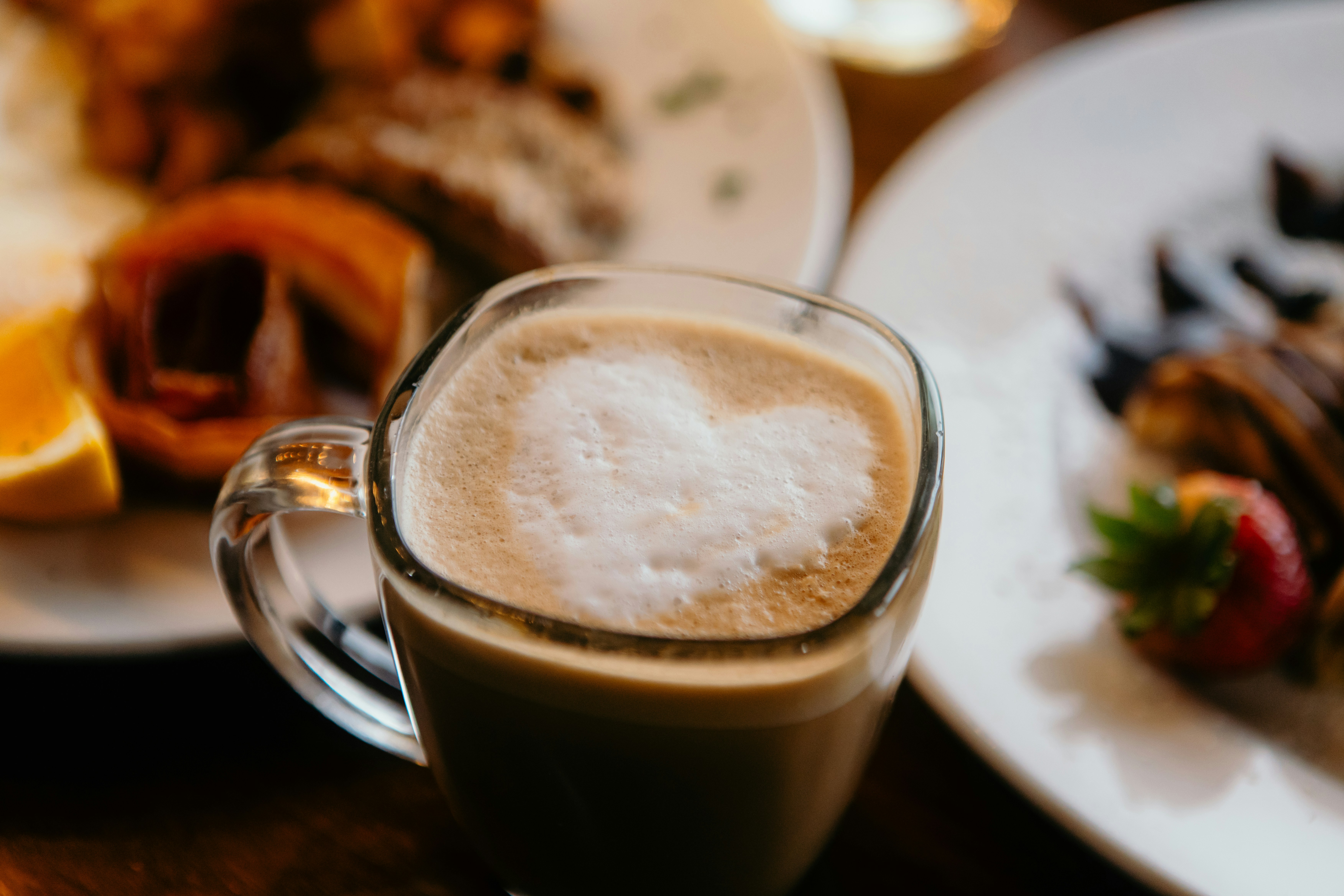 Latte in a glass mug beside pastries
