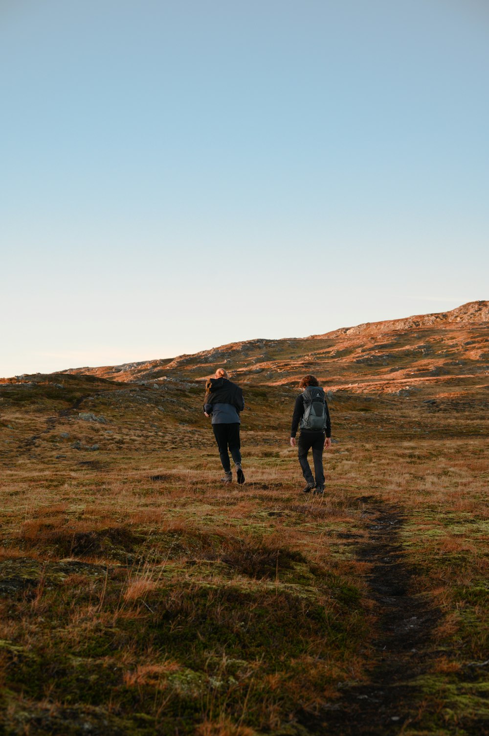 two people walking on a grassy hill