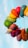 A vibrant arrangement of colorful, tightly packed balloons forming a semi-circular arc against a clear blue sky, showcasing a gradient transition from one balloon color to another.