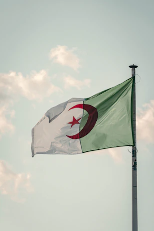 A scenic view of a school building with the Algerian flag waving gently in the breeze.