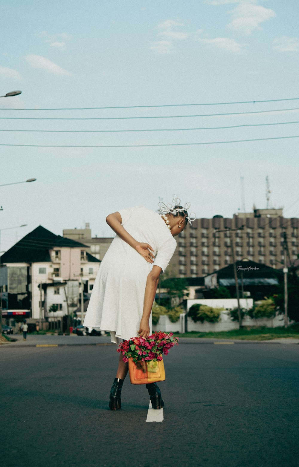 a person in a white dress carrying flowers on a street
