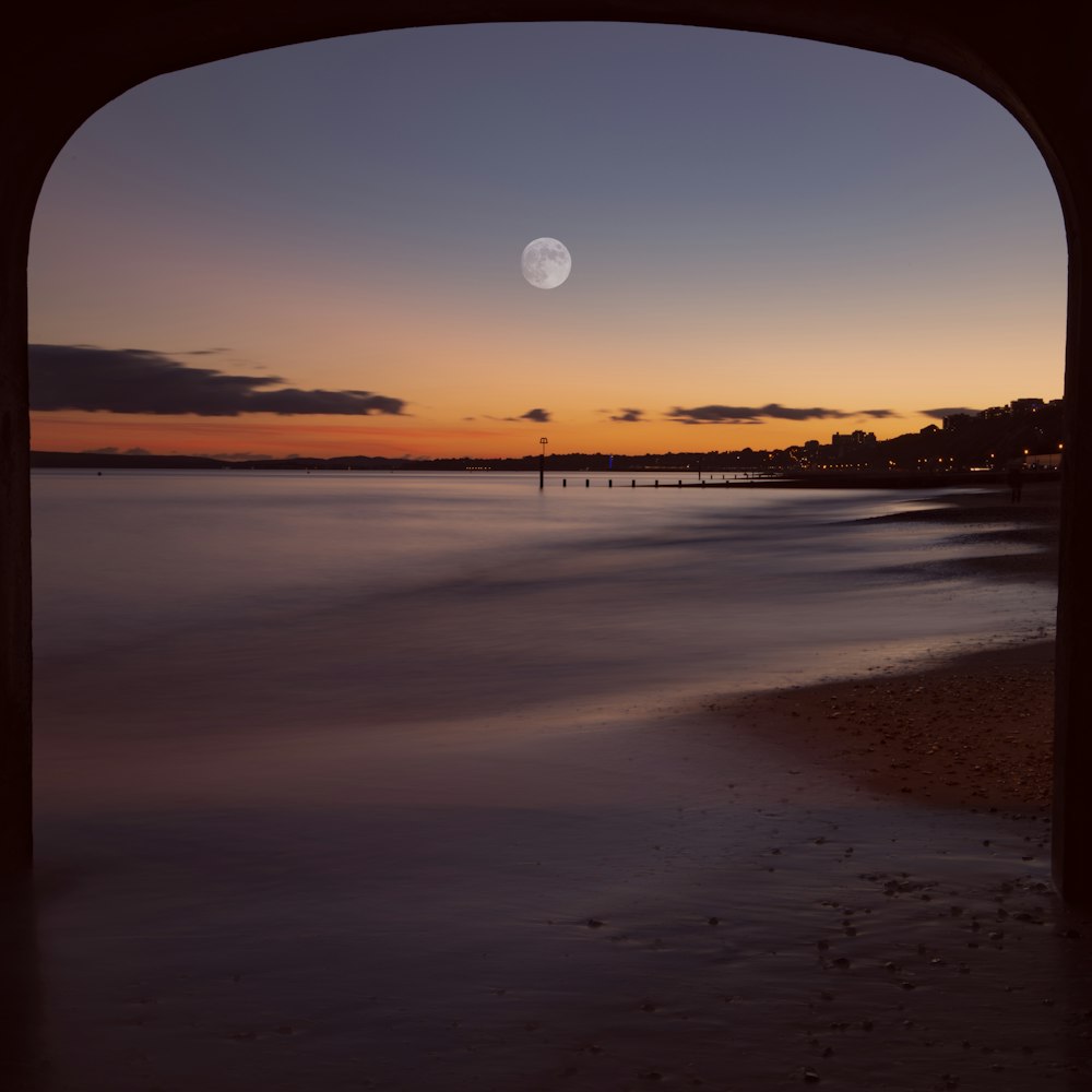 a beach with a moon in the sky