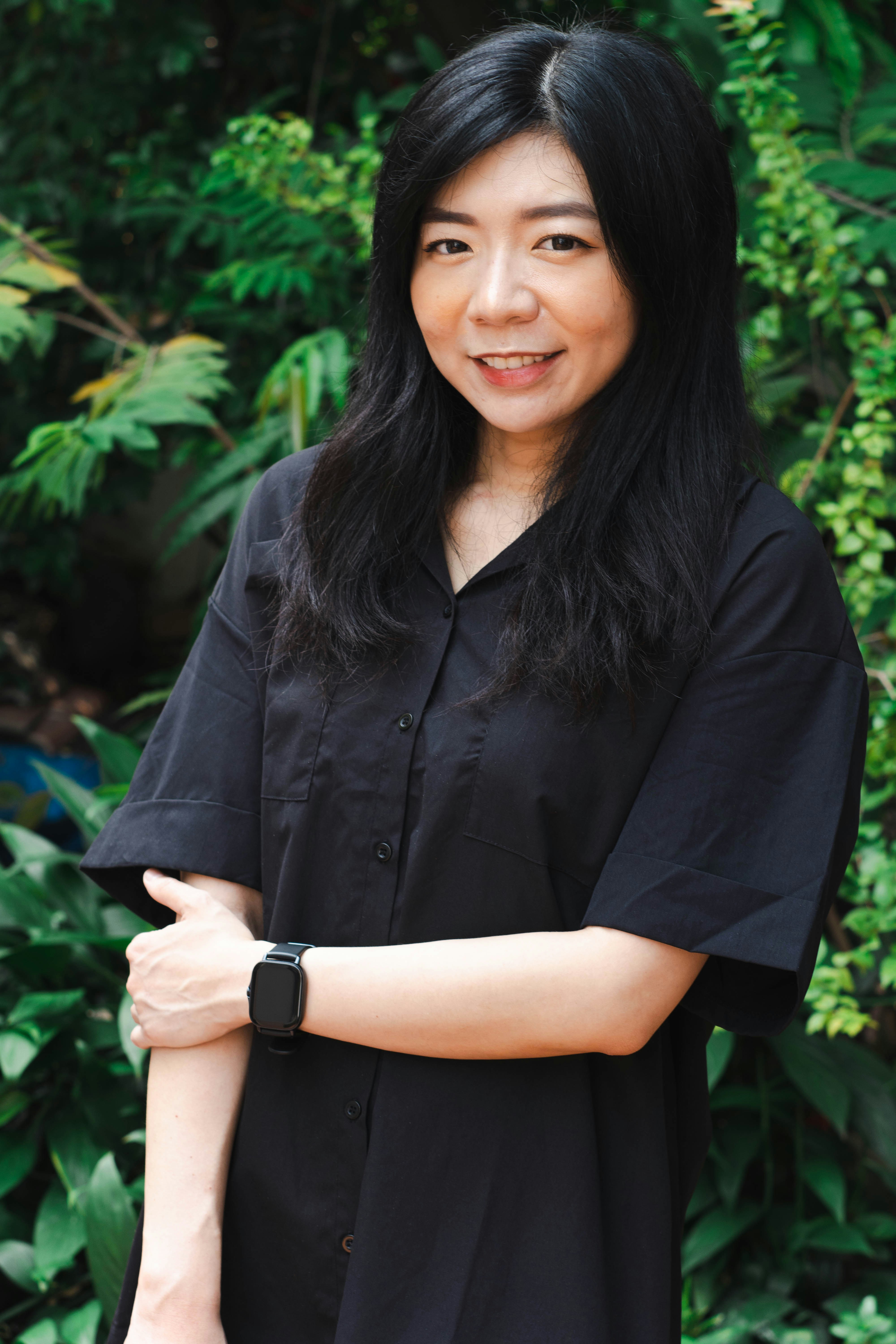 Asian female holds hand with a black dress at an outdoor scene