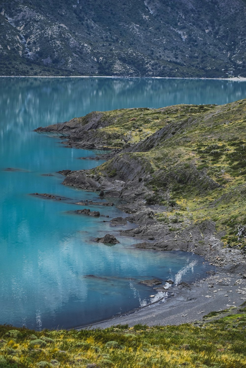 a rocky beach with a body of water in the background