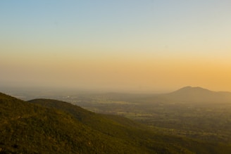 A serene landscape painting showing rolling hills under a glowing sunset.