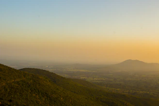 A serene landscape of rolling hills under a glowing sunset sky.