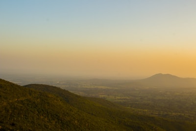 A serene landscape painting showing rolling hills under a glowing sunset.