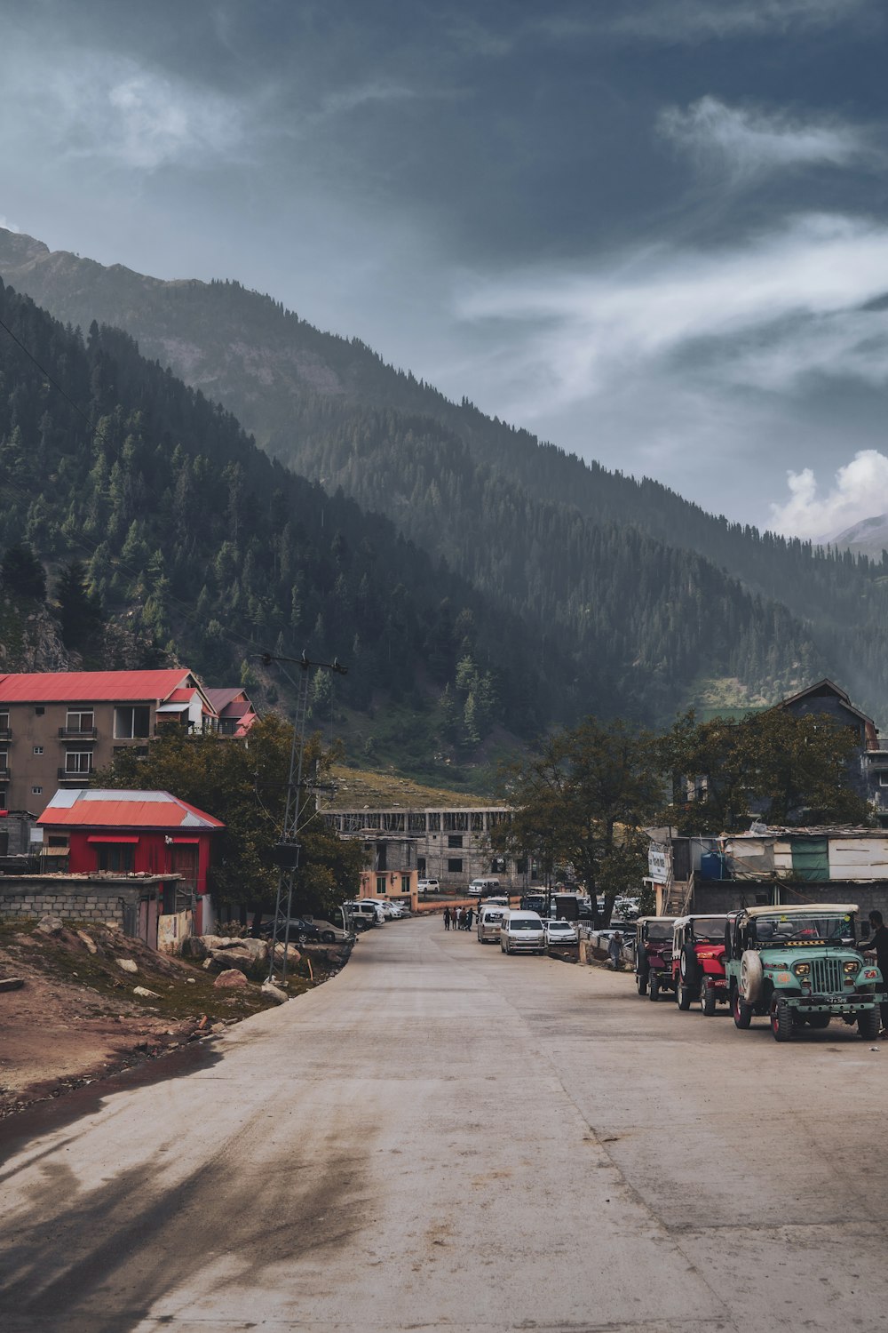 a road with cars and buildings by a mountain