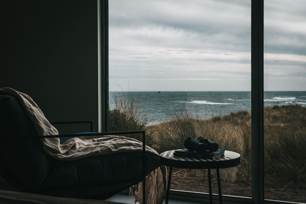 a table and chair by a window overlooking the ocean