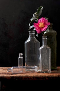 Elegant glass bottles arranged on a rustic wooden table surrounded by dried botanicals.