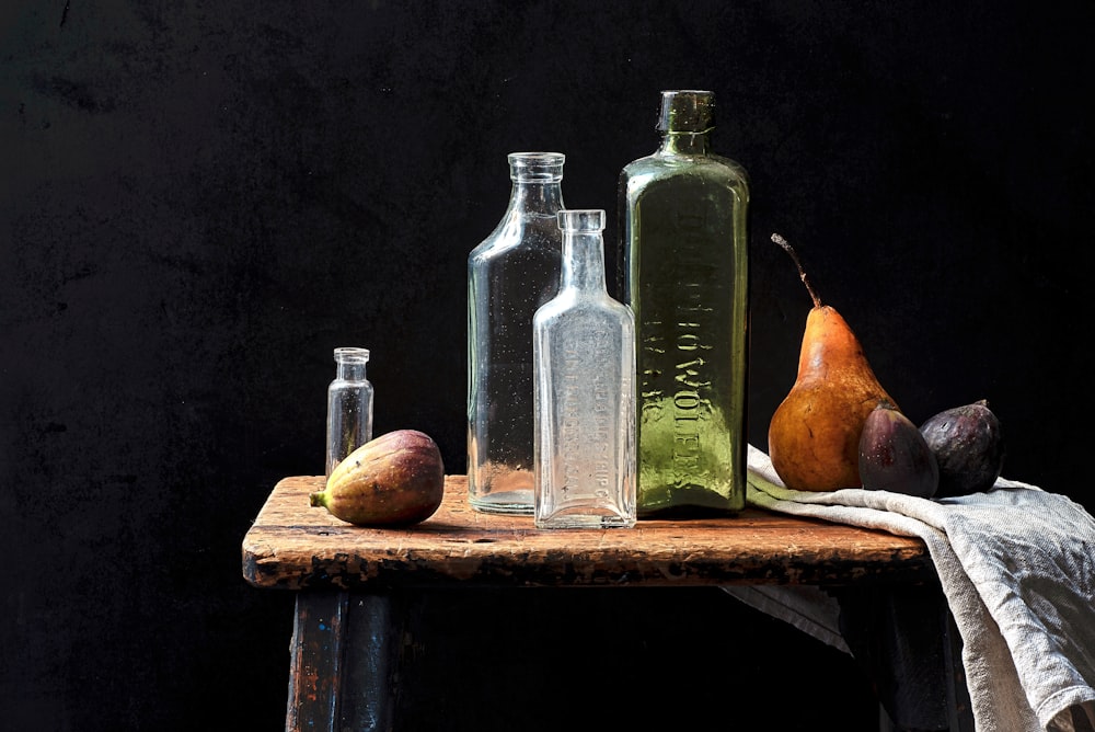 un gruppo di bottiglie di vetro e frutta su un tavolo
