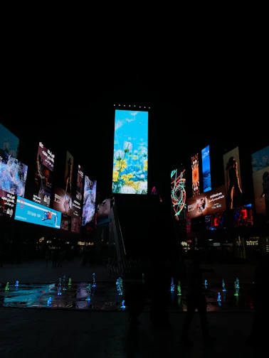 A vibrant outdoor digital billboard displaying colorful advertisements at sunset.