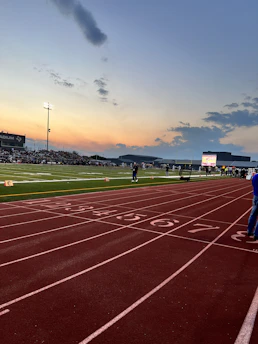 A dynamic sports scene with a runner in motion under bright stadium lights.