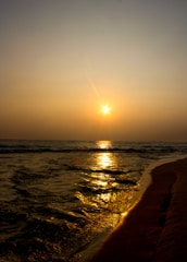 a beach with the sun setting