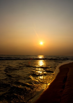 a beach with the sun setting