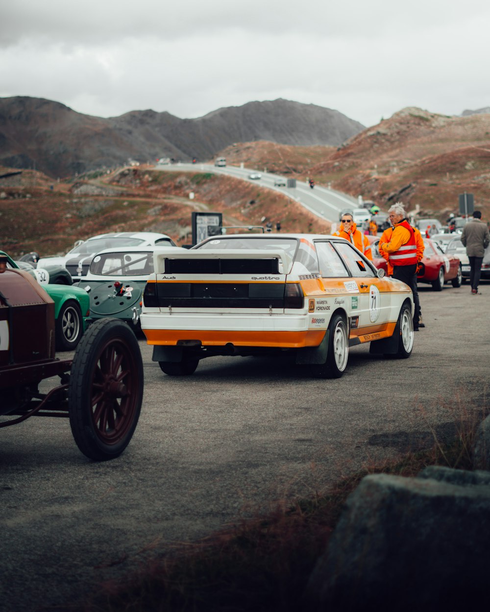 a group of people standing around a car on a road