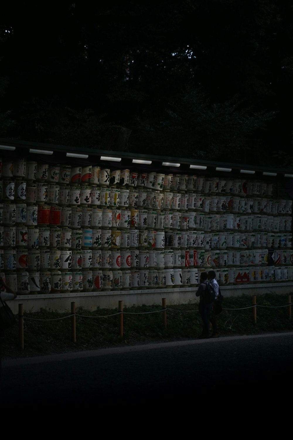 a man and woman standing in front of a wall of beer cans