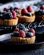 Close-up of a freshly baked fruit tart with vibrant berries on a rustic wooden table