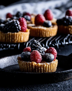 Close-up of a freshly baked fruit tart with vibrant berries on a rustic wooden table