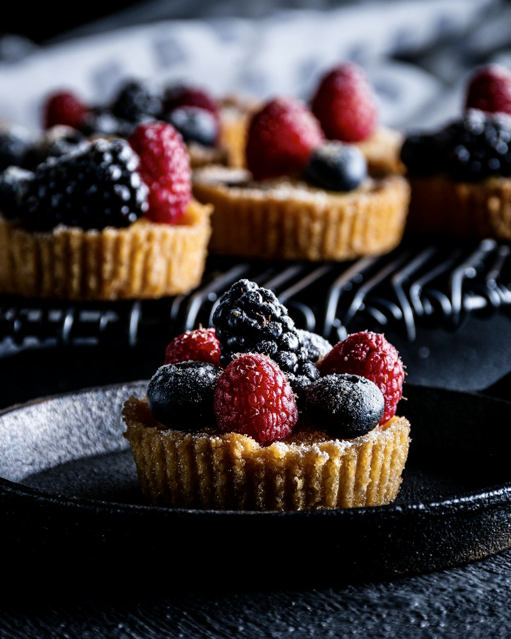 a plate of cupcakes with blueberries and chocolate frosting