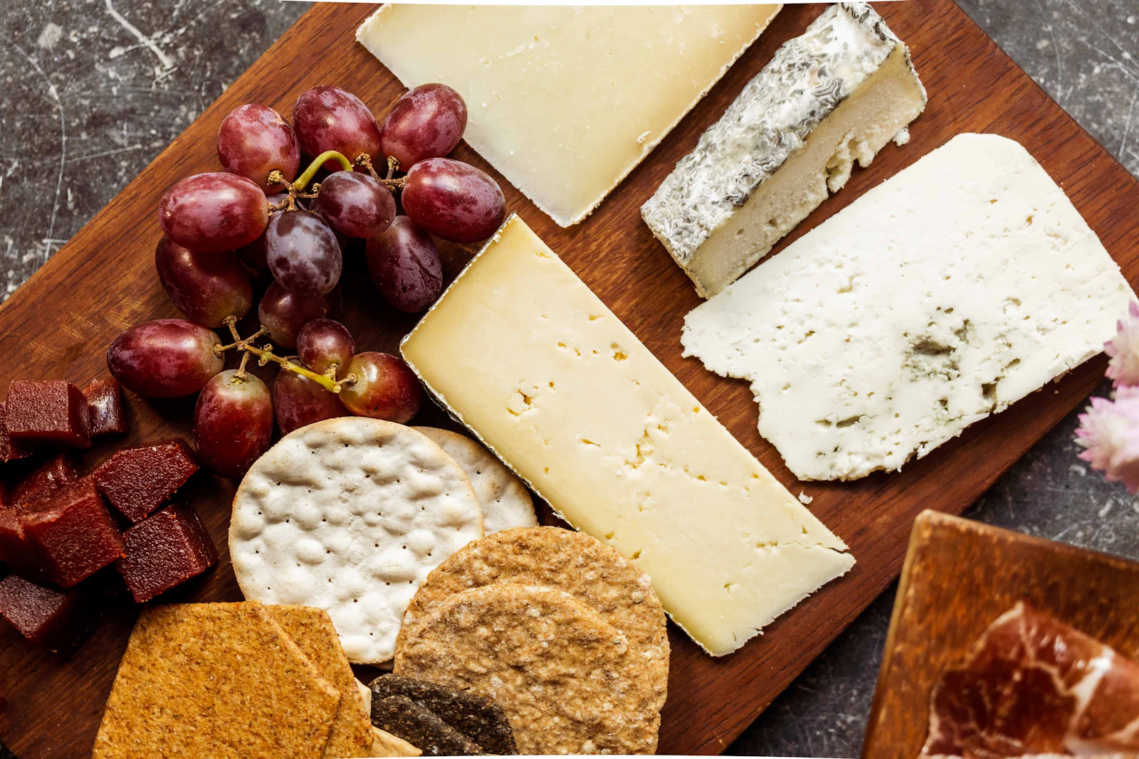 Plateau de fromages avec raisin et crackers sur une planche en bois