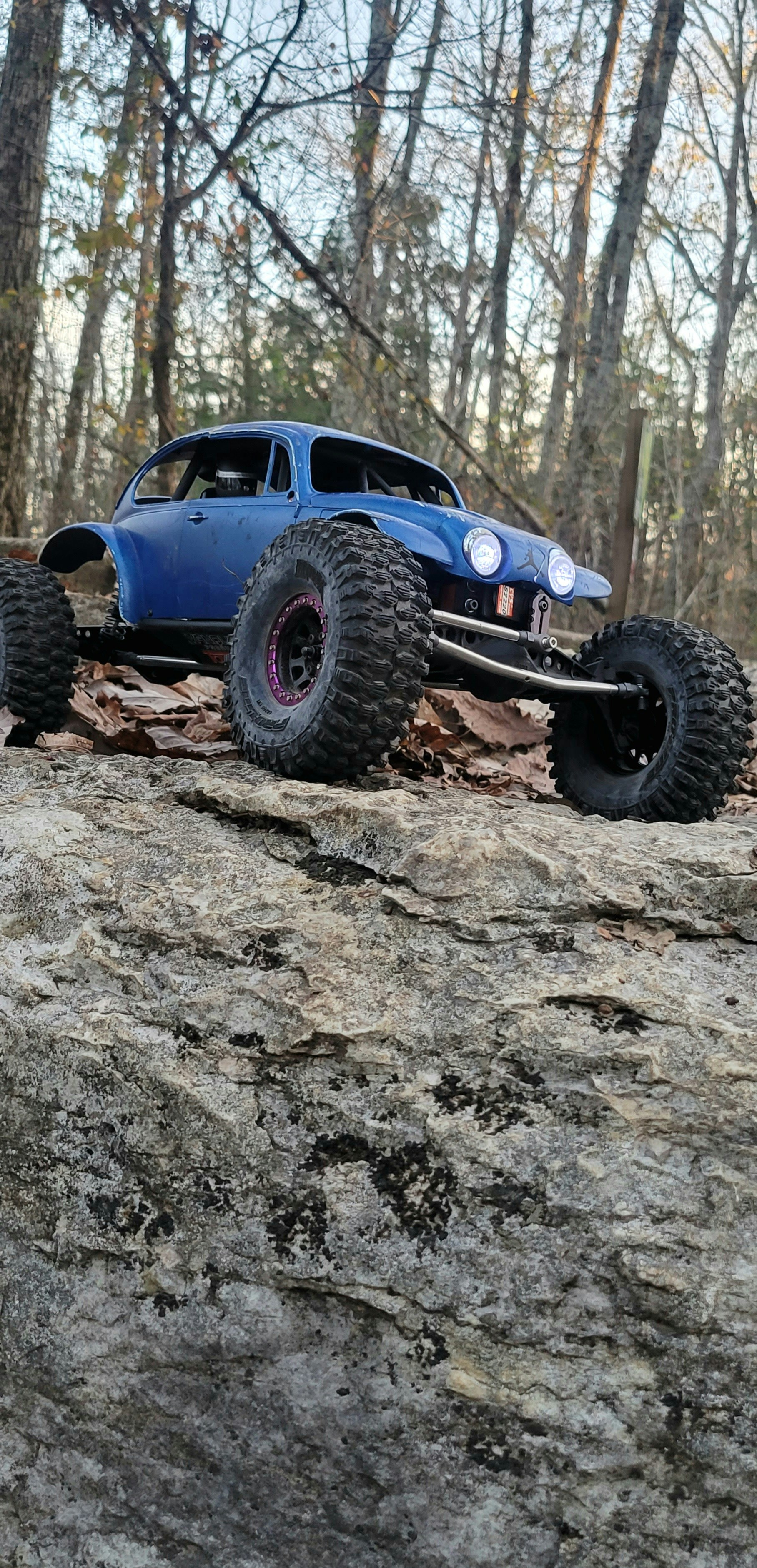 Rock crawler RC truck climbing steep rocky terrain in outdoor setting