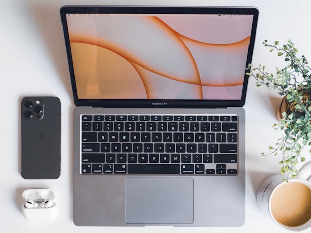 A minimalist workspace with a MacBook displaying an elegant iOS app interface.