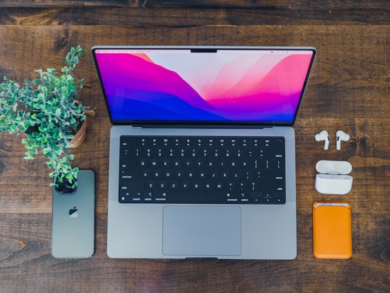 A cozy workspace with a laptop, smartphone, and tech gadgets neatly arranged on a wooden desk.
