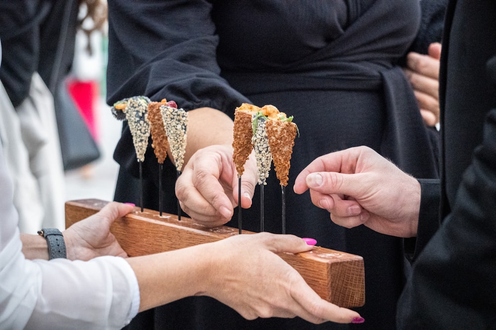 a group of hands holding a piece of wood