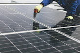 Photo capturing a technician performing maintenance on solar panels with professional tools.