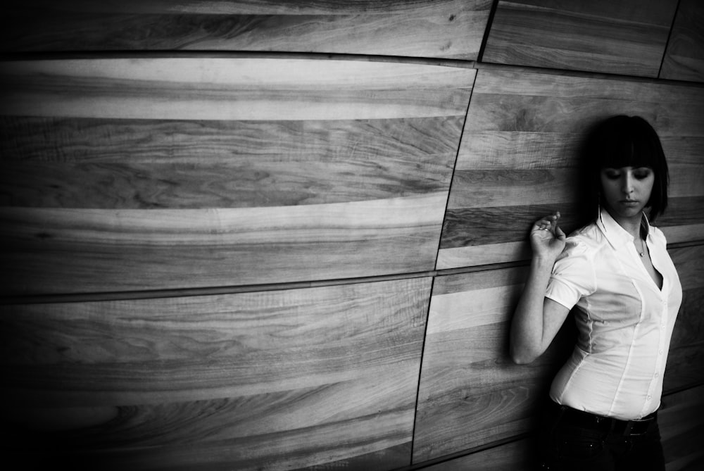 a woman standing next to a wood wall