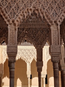 Intricate and ornate architectural details adorn a series of arches and columns. The stonework features elaborate geometric and floral patterns, demonstrating a high level of craftsmanship typical of Islamic architecture.