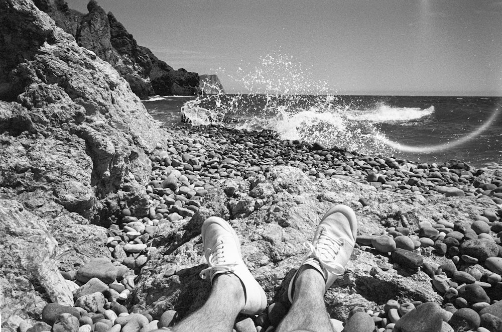 a person's feet on a rocky beach