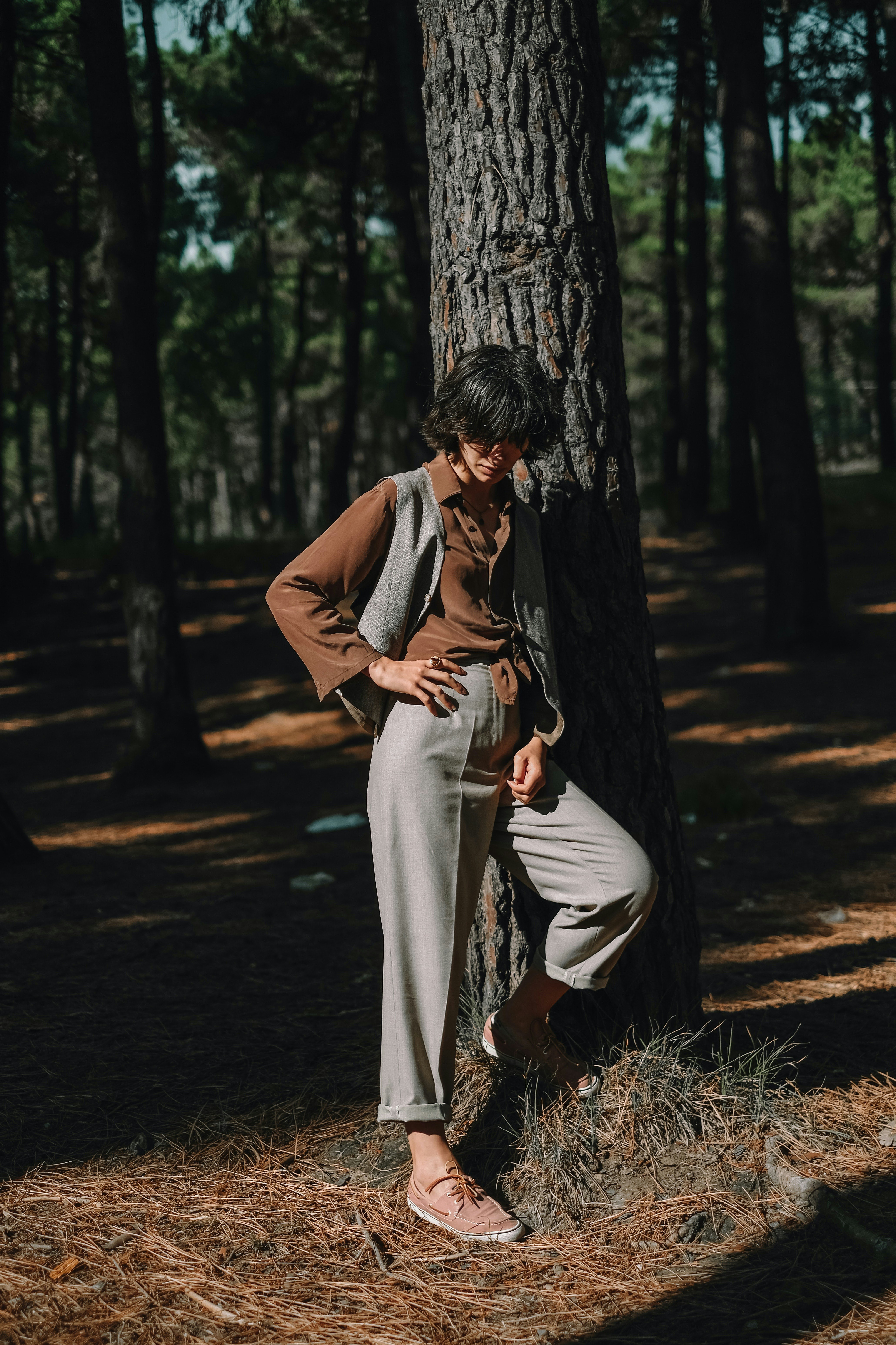 Woman in contemplative pose outdoors, soft dappled light through trees, expression of quiet strength and healing, warm tones
