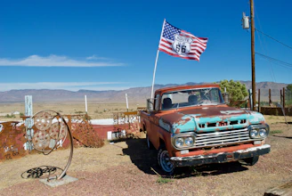 a truck parked on a dirt road with a flag on the side