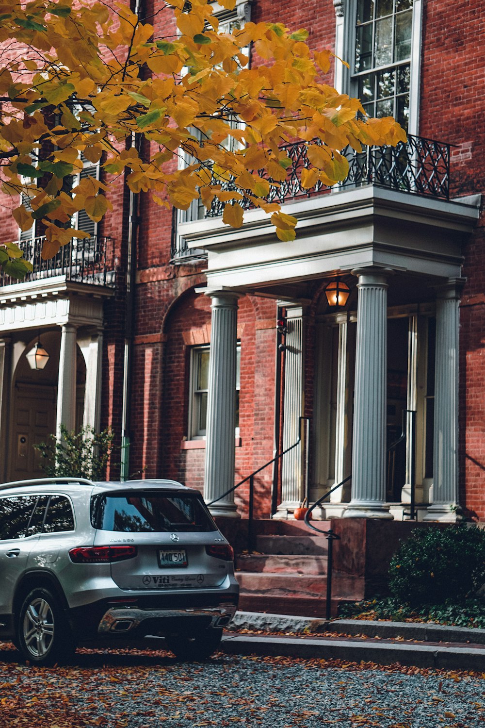 a car parked in front of a brick building with a tree in the front