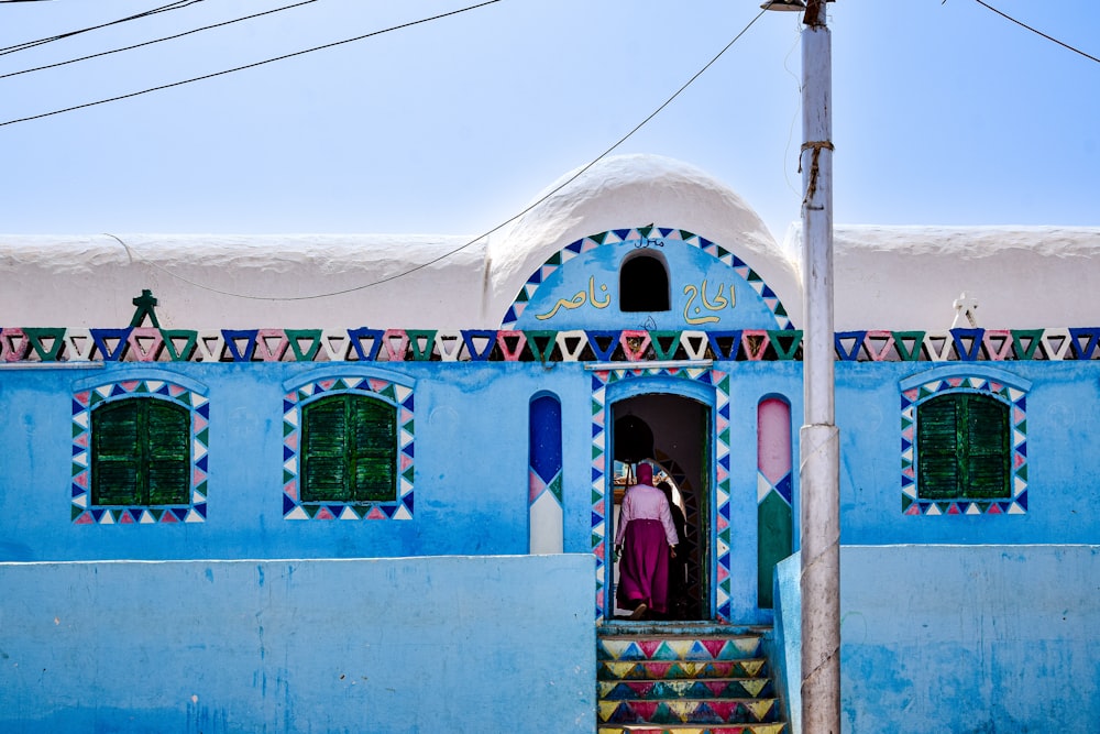 a person standing in a doorway of a blue building