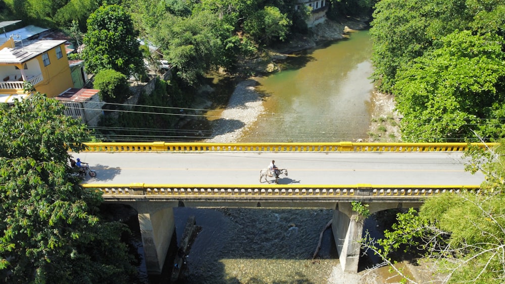 a person riding a motorcycle on a bridge over a river