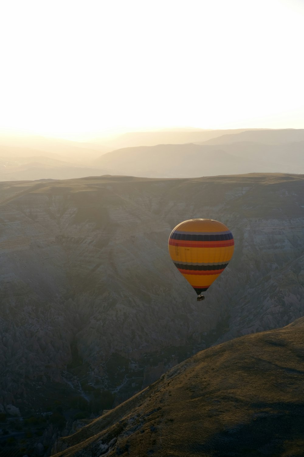 a hot air balloon flying over a valley