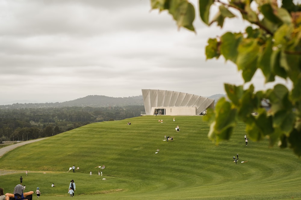 a group of people on a grassy hill with a building in the background