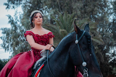 a person in a red dress riding a black horse