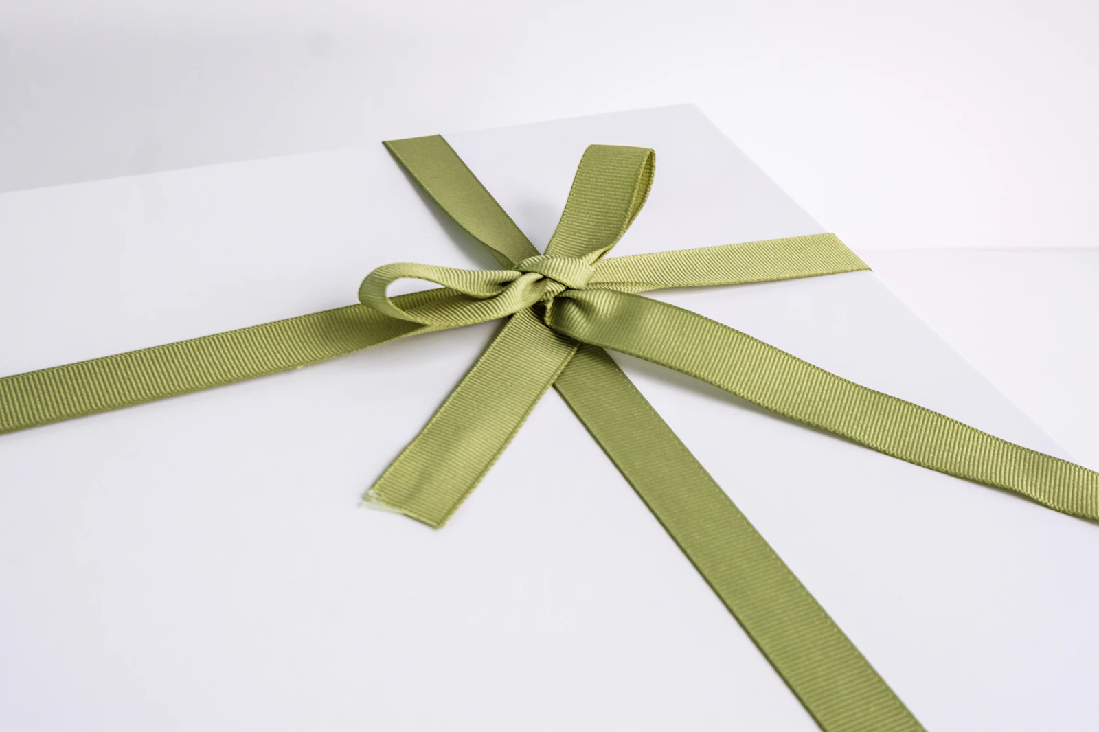 A green ribbon tied in a bow on a white surface