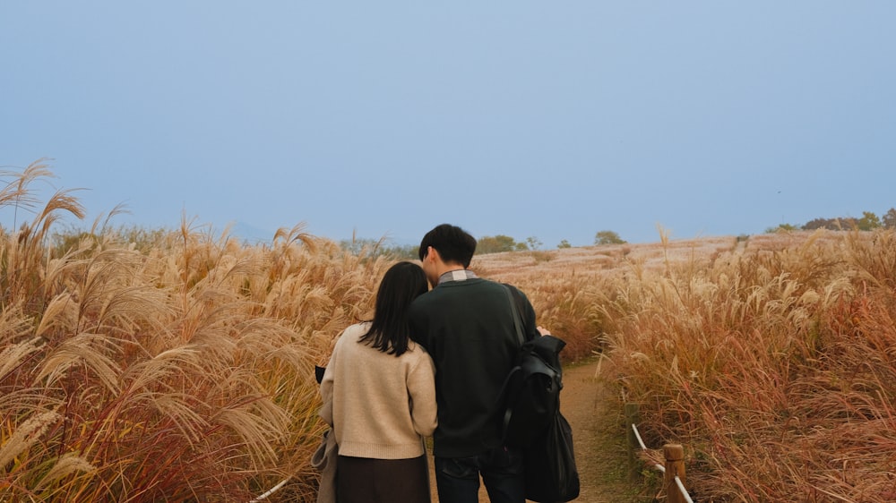 a group of people walking through a field of wheat