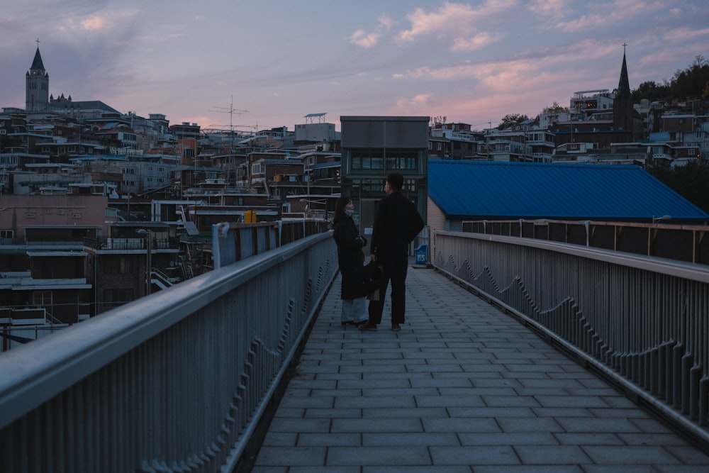 a man and woman walking on a bridge over a city