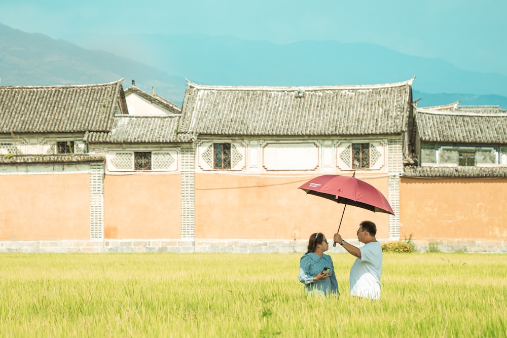 a couple of people sit under an umbrella in front of a large building