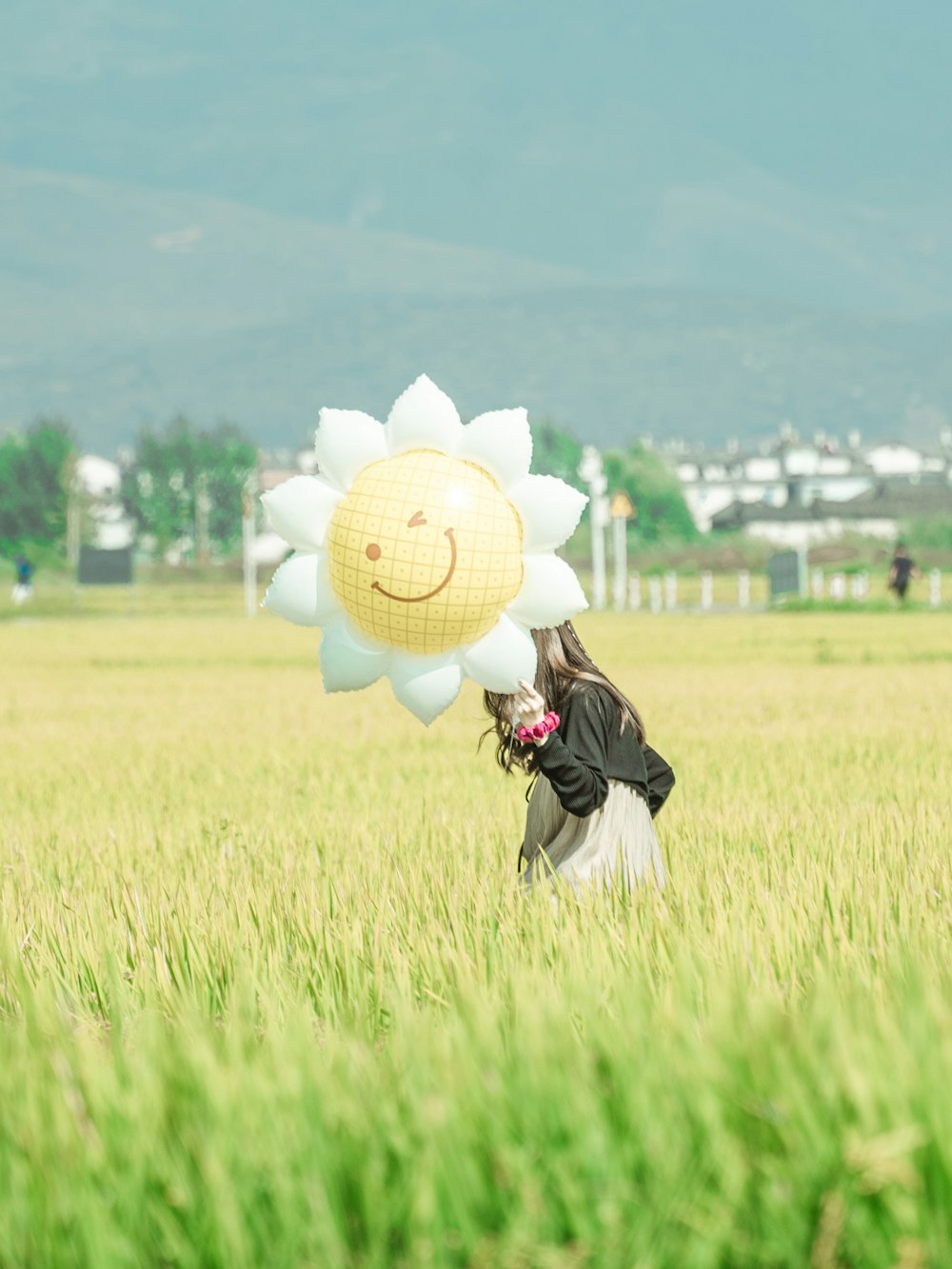 a person kneeling in a field with a large white flower on the head