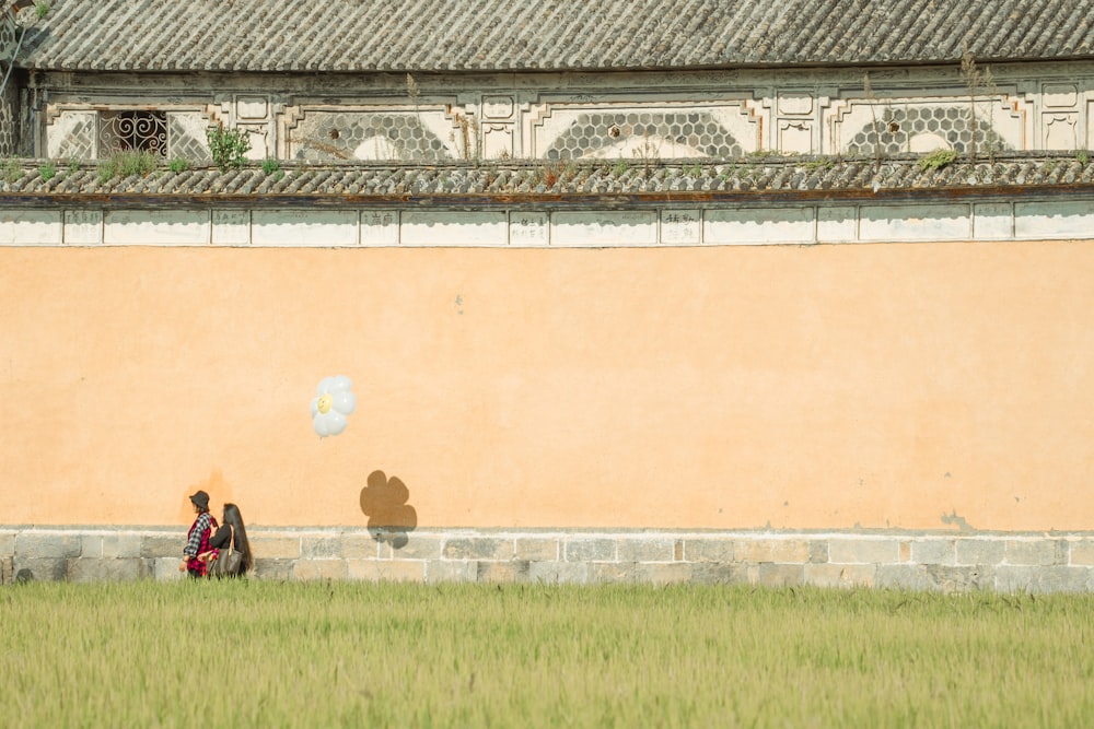 a person and a dog sitting on grass in front of a wall