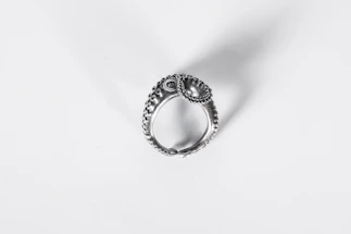 Close-up of hands sketching a custom silver ring design on paper with nature-inspired motifs.