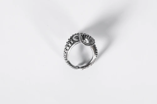 Close-up of a delicate silver ring with an intricate leaf design resting on a soft linen cloth.